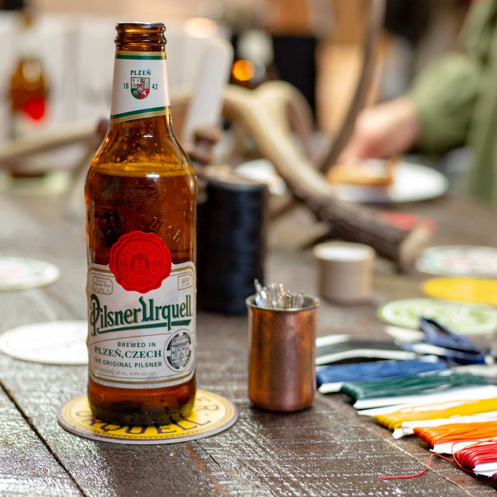 Pilsner Urquell bottle beside leathercraft tools