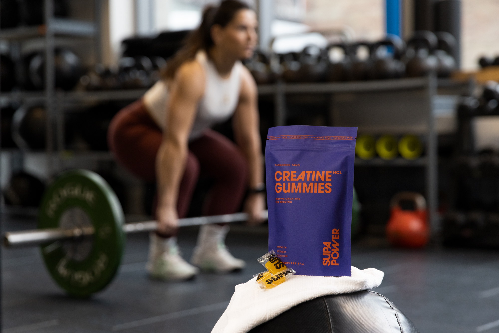 SUPA POWER tangerine creatine gummies photographed in a working gym