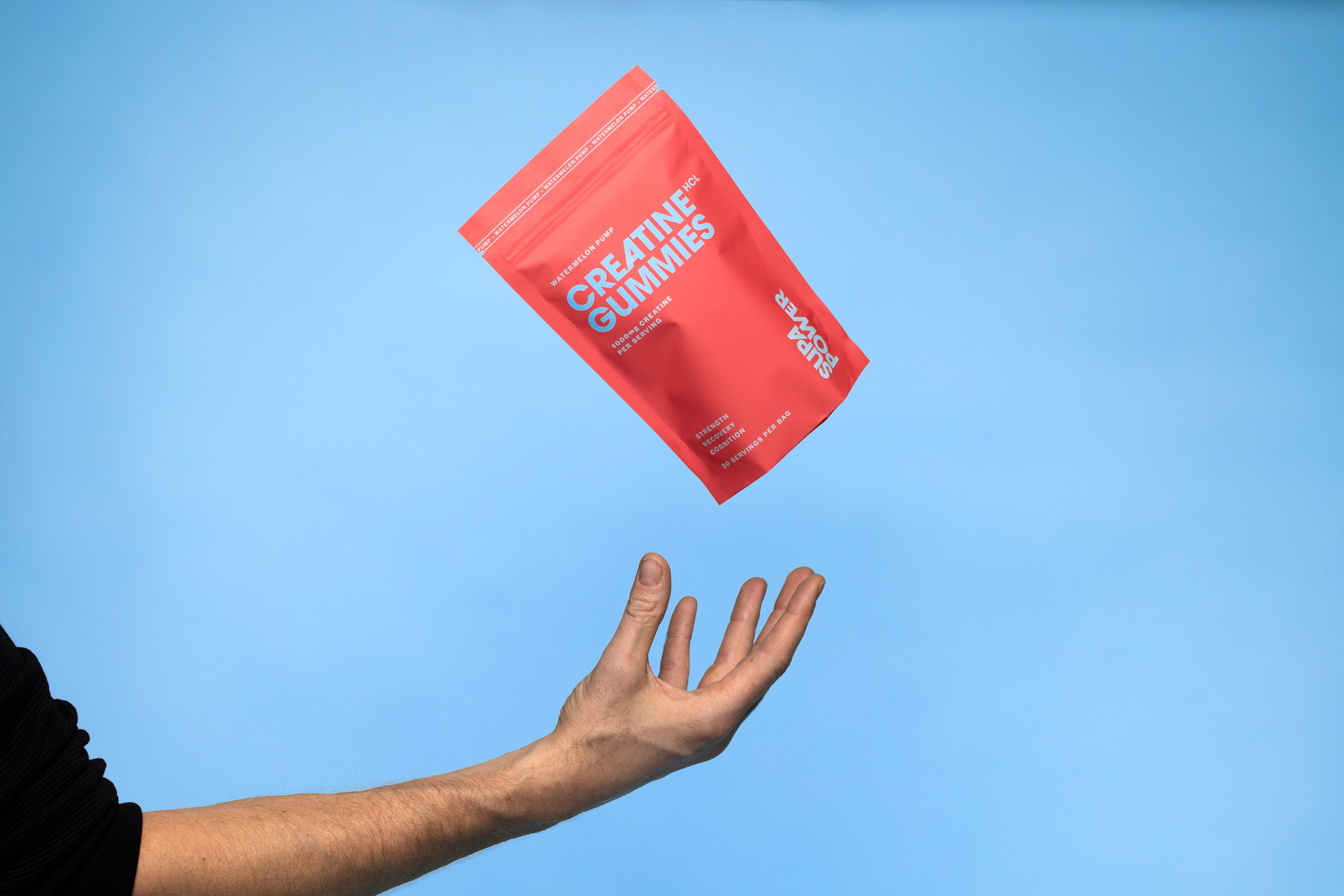 SUPA POWER watermelon creatine gummies tossed above a hand