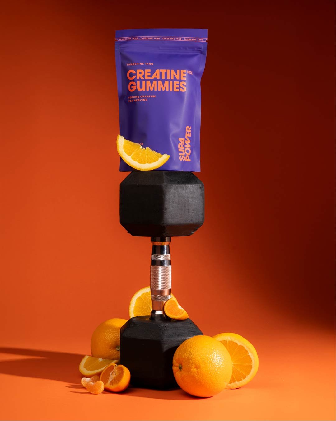 Creatine gummies on a dumbbell with oranges