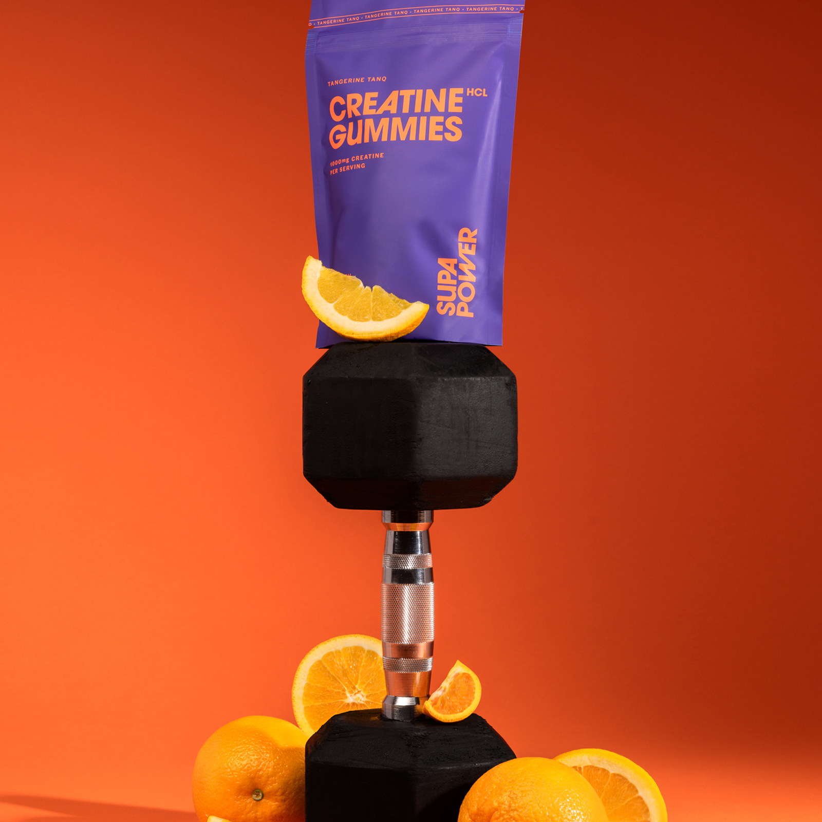 Tangerine creatine gummies balanced on a dumbbell